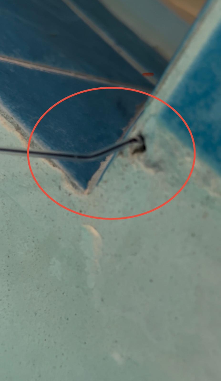 Dye test at a blue waterline tile corner where missing grout opens into the pool structure, marked with a red circle
