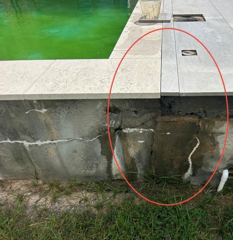 White calcium efflorescence trails running down the exterior concrete wall of a raised pool with horizontal cracking