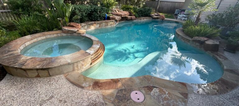 Backyard swimming pool with a raised spa, rock waterfall, tanning ledge and flagstone deck
