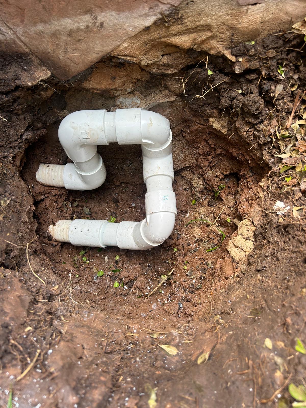 New PVC offset built from four elbows spliced into a pool line inside a small excavation beside flagstone coping