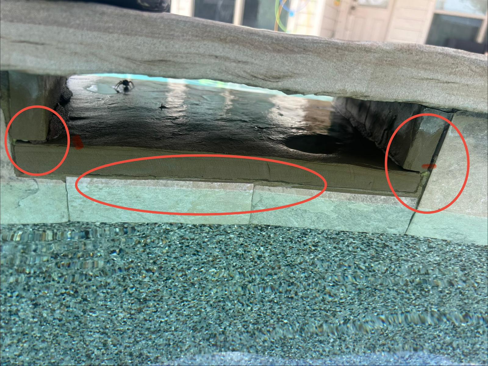 Inspection photo with cracks circled in red along the horizontal joint and end returns of a stone spa spillover